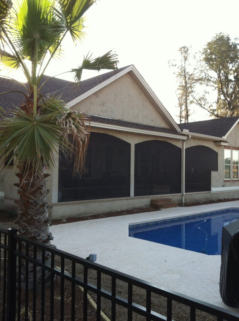 Screened porch enclosure on a Baxley Georgia home surrounded by dense pine tree canopy.