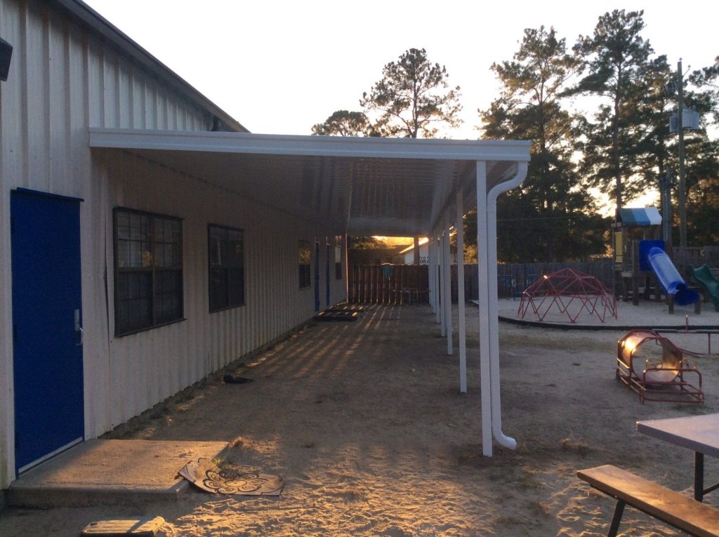 Aluminum patio cover installed on a Lyons Georgia home surrounded by high tree canopy in Toombs County.